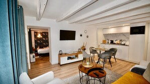 A modern living room with a sofa, coffee table, and dining area. There is a kitchen with a microwave and a sink. - ELEGANCE in the heart of the old town 4 **** (Annecy)