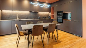 A modern kitchen with a marble backsplash, built-in appliances, and a dining area with a wooden table and chairs. - L'OASIS T3 Centre ville (Annecy)