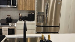A modern kitchen with stainless steel appliances, a microwave, a kettle, and a sink with a faucet.