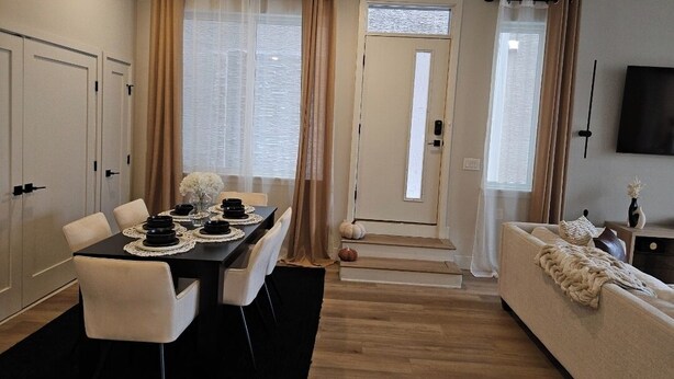 A modern living room with a dining area, featuring a sofa, a coffee table, and a dining table set with plates and bowls.