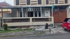 A two-story building with a covered porch and a gated entrance. - Hotel O Homestay Adreena Syariah (Purwokerto)
