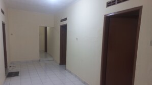 A corridor with tiled flooring, white walls, and brown doors. - Hotel O Homestay Adreena Syariah (Purwokerto)