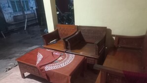 A room with a wooden sofa set, a matching wooden table, and a patterned tablecloth. - Hotel O Homestay Adreena Syariah (Purwokerto)