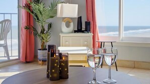 Une pièce avec vue sur l’océan, une table avec des bougies et des verres, une lampe et une plante.