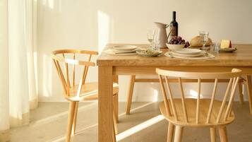 Una mesa de madera con platos, vasos, una botella y un bol de uvas.