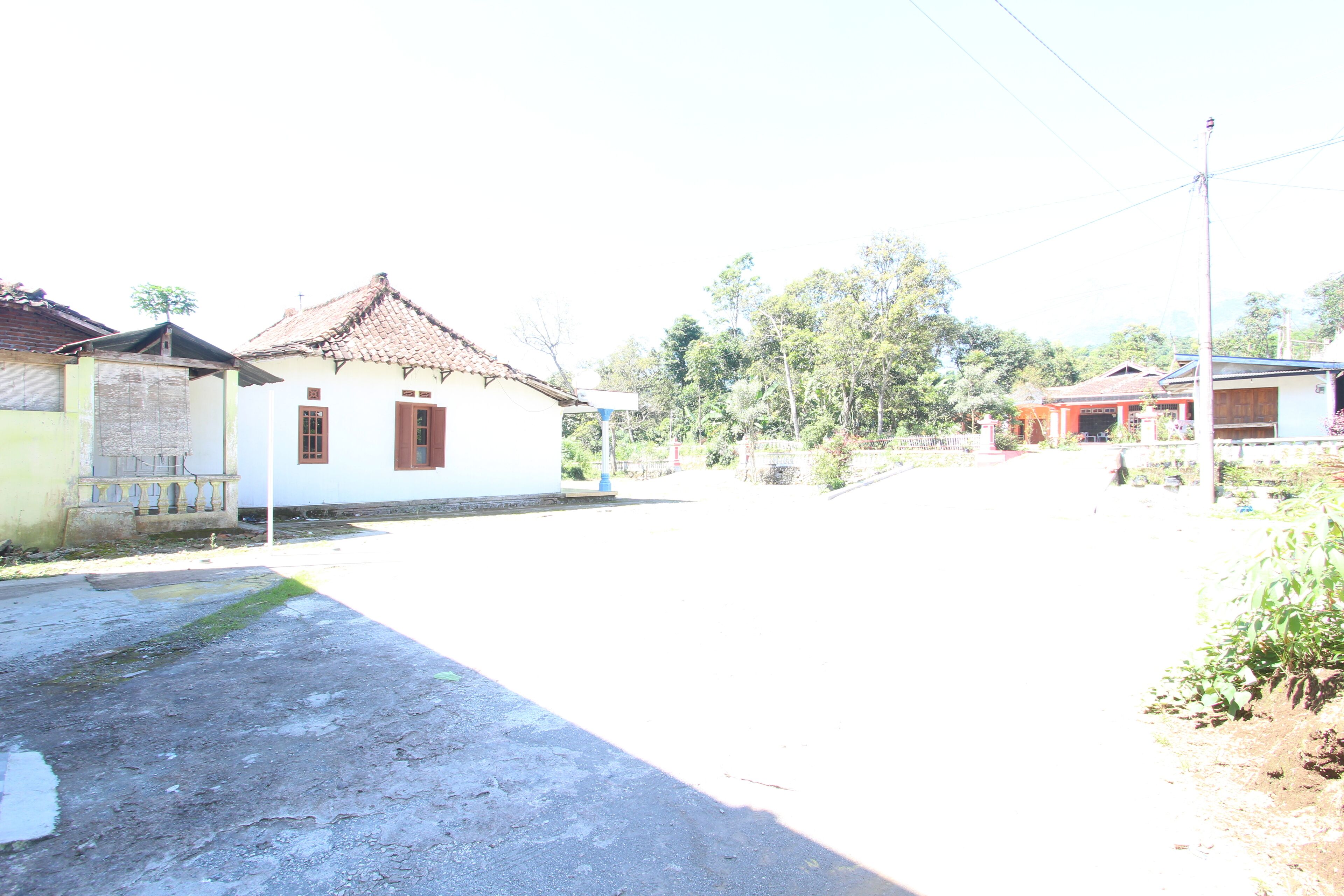 A quiet street with a white building with a tiled roof and a small porch.
