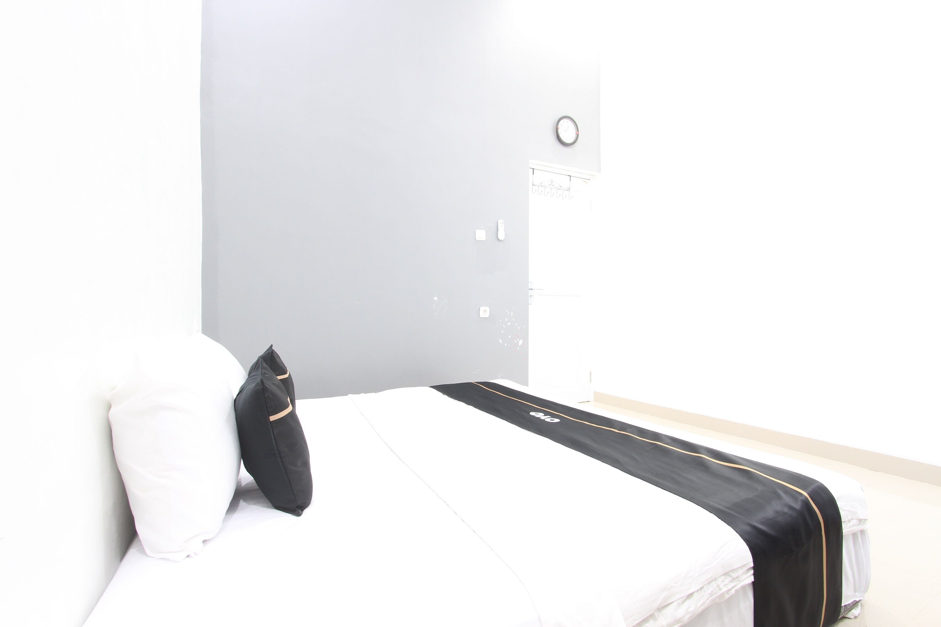 Un dormitorio con cama, almohada, mesita de noche y un reloj de pared.