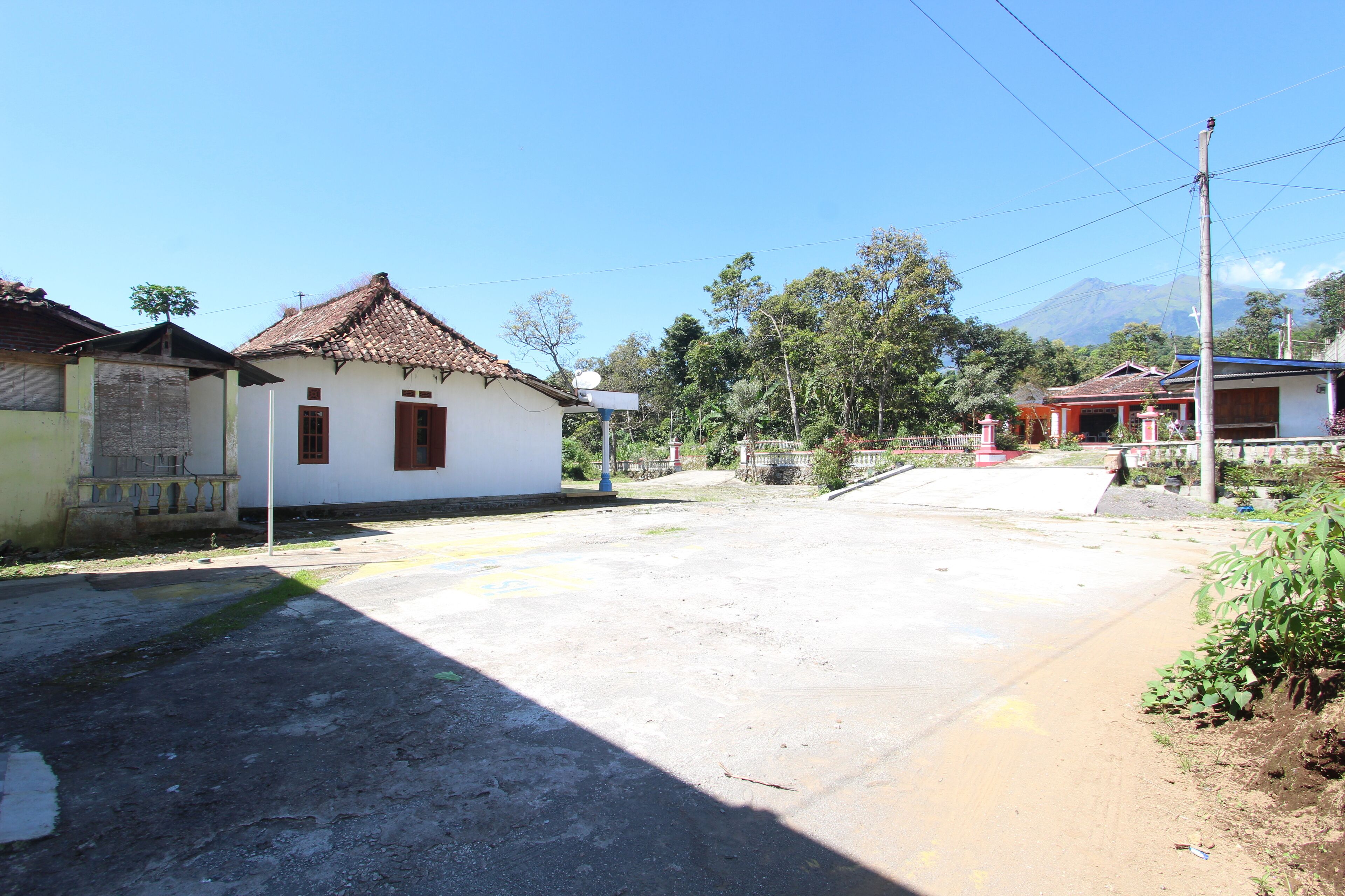 Una calle tranquila con un edificio blanco de tejado con tejas y un pequeño porche.
