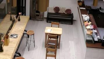 Un intérieur moderne avec de hauts plafonds, des luminaires suspendus et un espace salon central agrémenté de tabourets et de tables.
