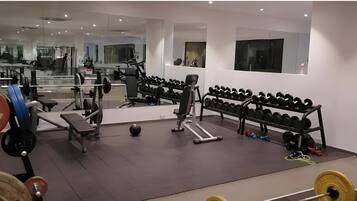 Une salle de sport équipée de matériel de musculation, de tapis de course et de ballons d’exercice.