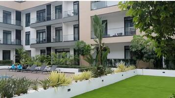 Un immeuble résidentiel à plusieurs étages, doté de balcons, d’une piscine et d’un aménagement paysager bien entretenu.