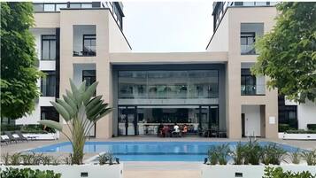 Un hôtel moderne doté d’une façade en verre, d’un espace extérieur aménagé et d’une piscine.