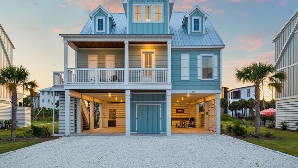 A two-story beachfront house with a balcony, a covered front porch, and a driveway leading to the entrance. - Pet-Friendly Retreat with Hot Tub and Views (Port St. Joe)