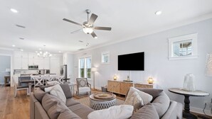 A modern living room with a large gray sectional sofa, a dining area with white cabinets and a TV mounted on the wall. - Pet-Friendly Retreat with Hot Tub and Views (Port St. Joe)