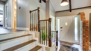 A staircase with wooden steps and metal railings, leading to a landing with a door and a brick wall. - Chic Family-friendly Home in Riverside: 7 Mi to KC (Riverside)