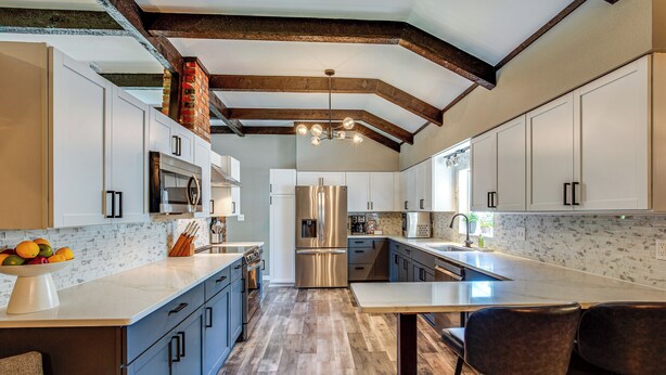 A modern kitchen with white cabinets, stainless steel appliances, and a wooden ceiling. - Chic Family-friendly Home in Riverside: 7 Mi to KC (Riverside)