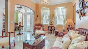 A spacious living room with a glass coffee table, a sofa, and a dining area with chairs and a table. - Near Parks: Port St Lucie Home w/ Private Pool! (Port Saint Lucie)