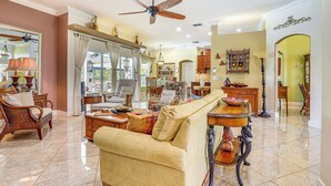 A spacious living room with a ceiling fan, a sofa, a coffee table, and a dining area with a table and chairs. - Near Parks: Port St Lucie Home w/ Private Pool! (Port Saint Lucie)