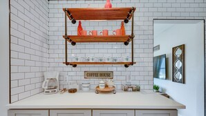 A kitchen with white tiled walls, a coffee station, and a sign that reads "Coffee House."