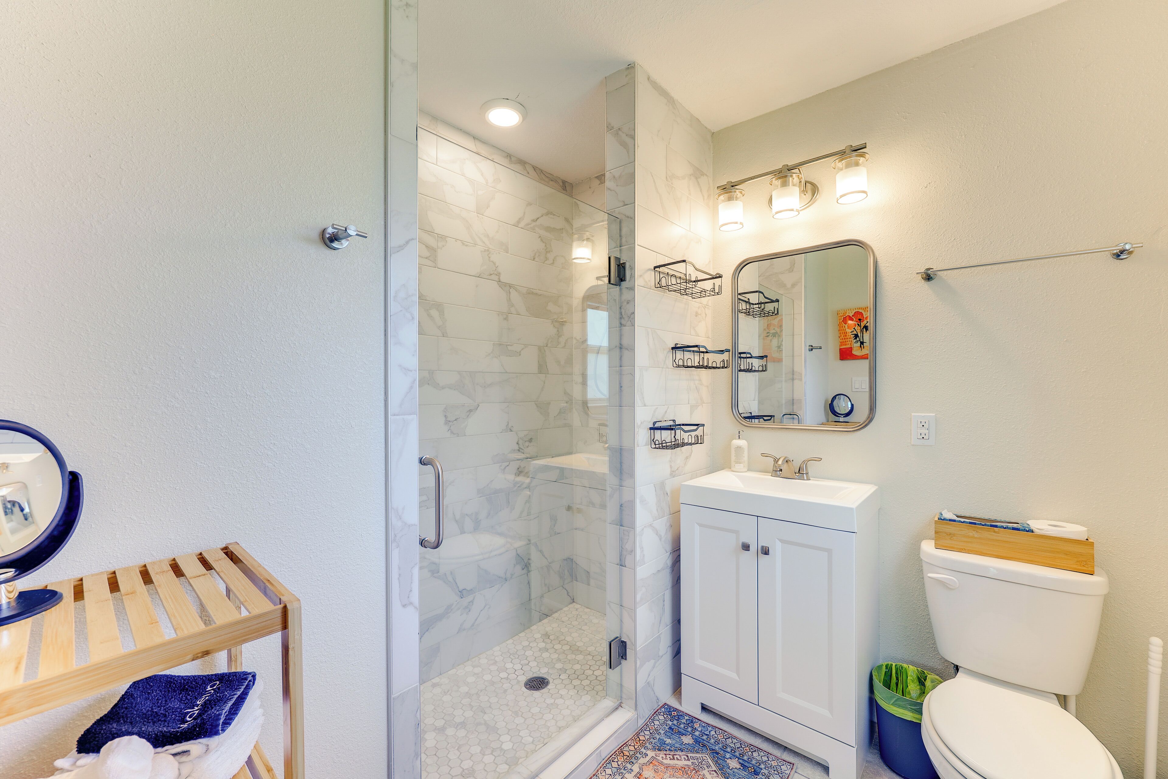 Un baño moderno con ducha envuelta en vidrio, un lavabo blanco y un inodoro.