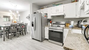 A modern kitchen with white cabinets, stainless steel appliances, and a granite countertop.