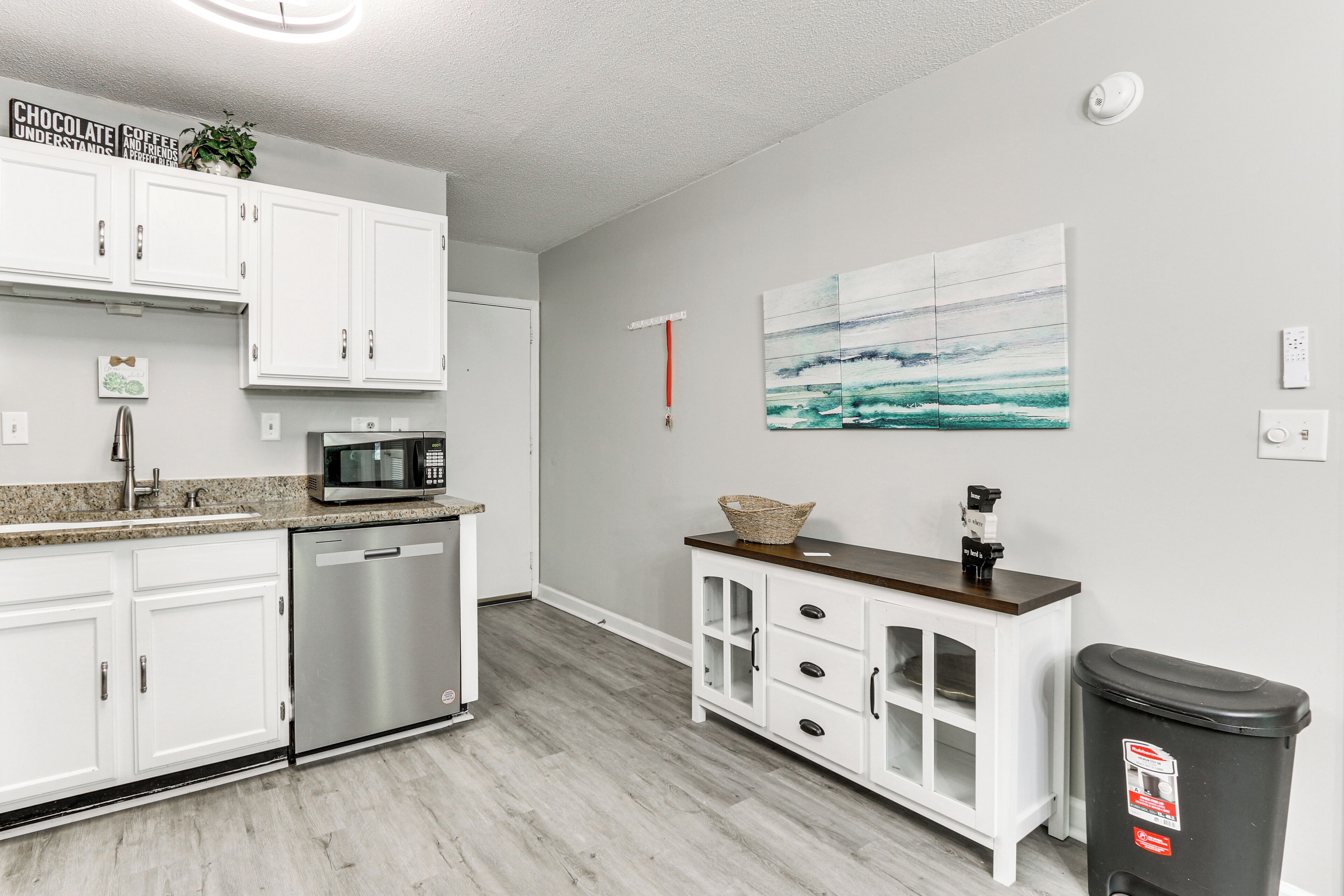 A modern kitchen with white cabinets, stainless steel appliances, and a wooden countertop.