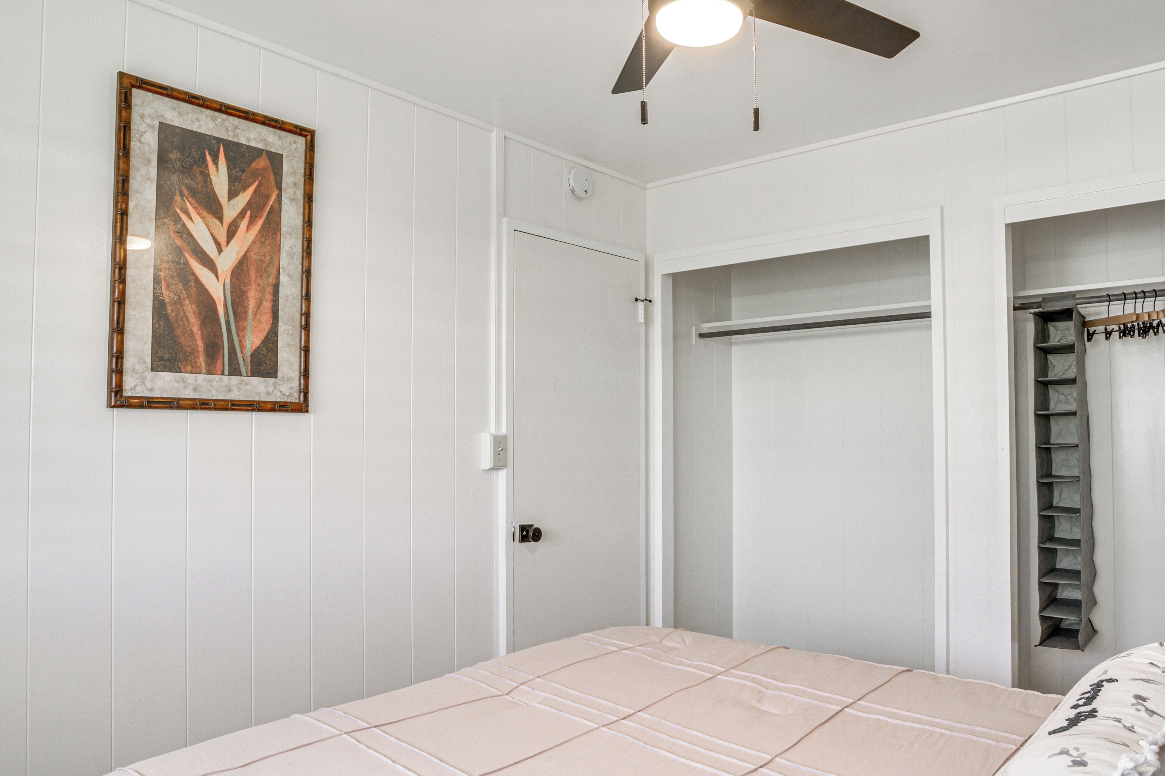 A bedroom with a bed, a wardrobe, and a ceiling fan.