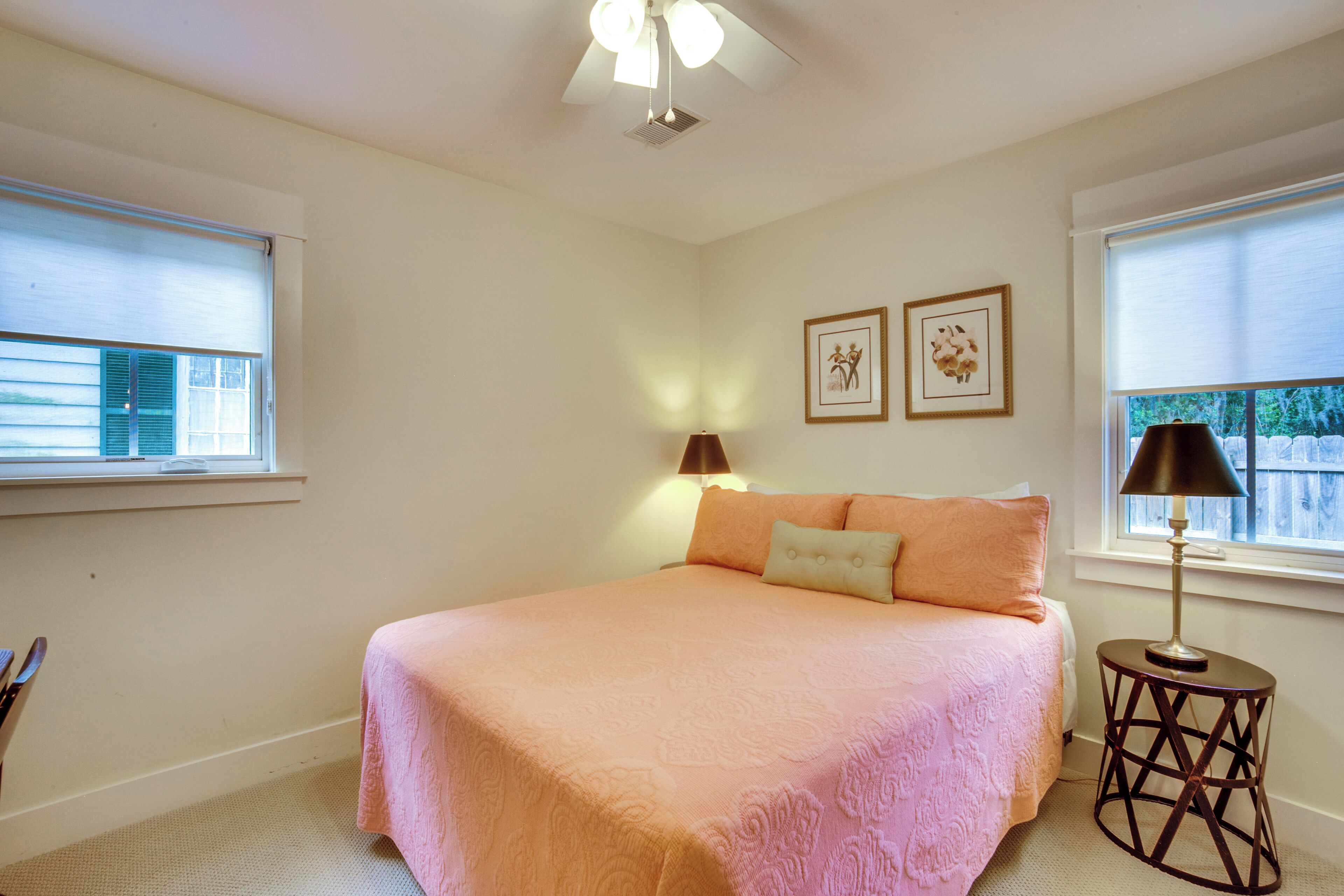 A bedroom with a large bed, two bedside lamps, and a ceiling fan.