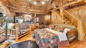 A log cabin interior with a large bed, wooden staircase, and rustic decor. - Lake & Beach Access at Lake Luzerne Cabin! (Lake Luzerne)