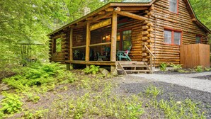 A log cabin with a porch, a sign reading "Bucktail Mt Lodge", and a forested backdrop. - Lake & Beach Access at Lake Luzerne Cabin! (Lake Luzerne)