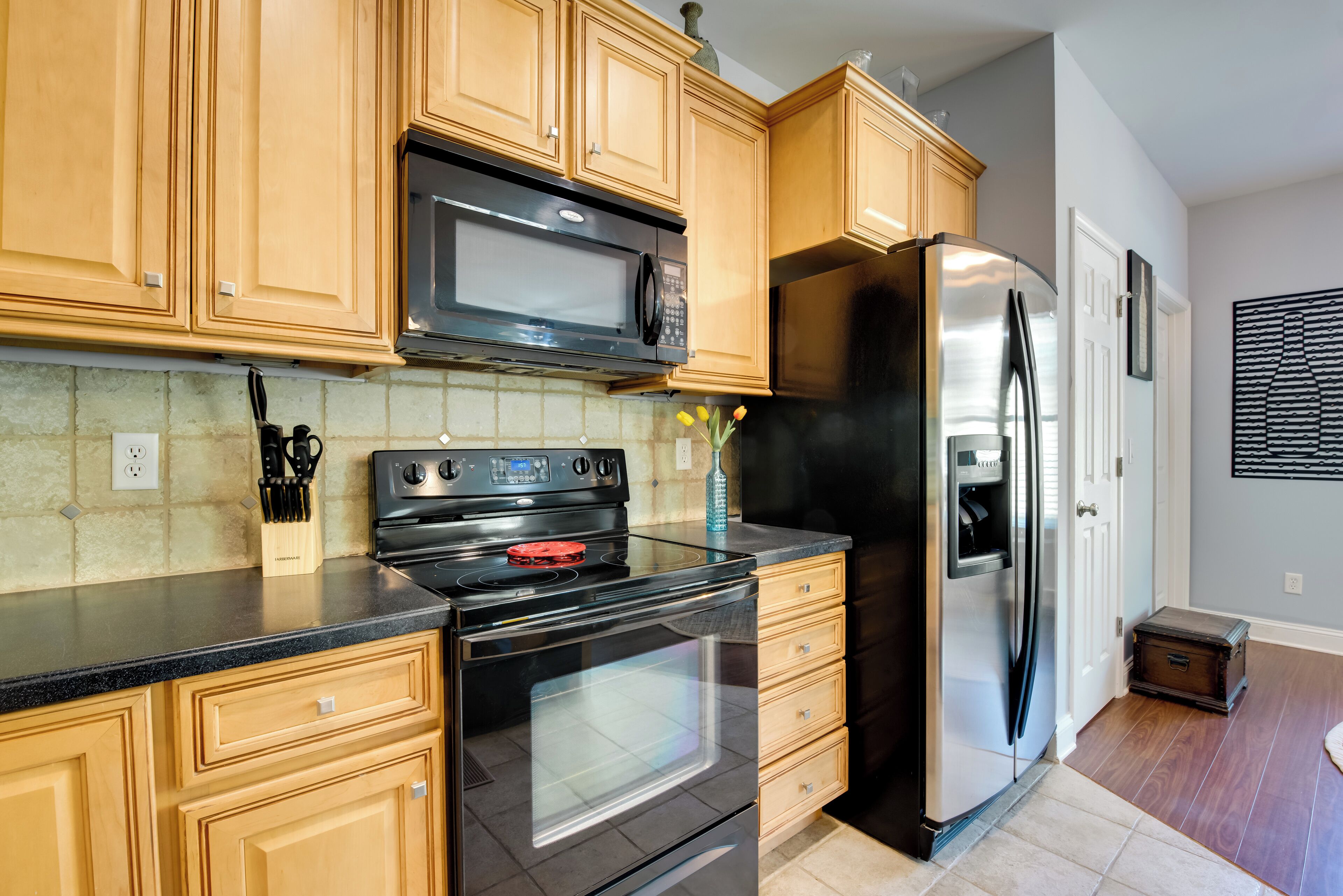 A kitchen with wooden cabinets, a stainless steel refrigerator, a microwave, and a stove.