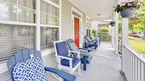 A porch with blue and white Adirondack chairs, a red door, and hanging flower baskets. - 3 Mi to Beaches! Charming Bluffton Escape w/ Yard (Bluffton)