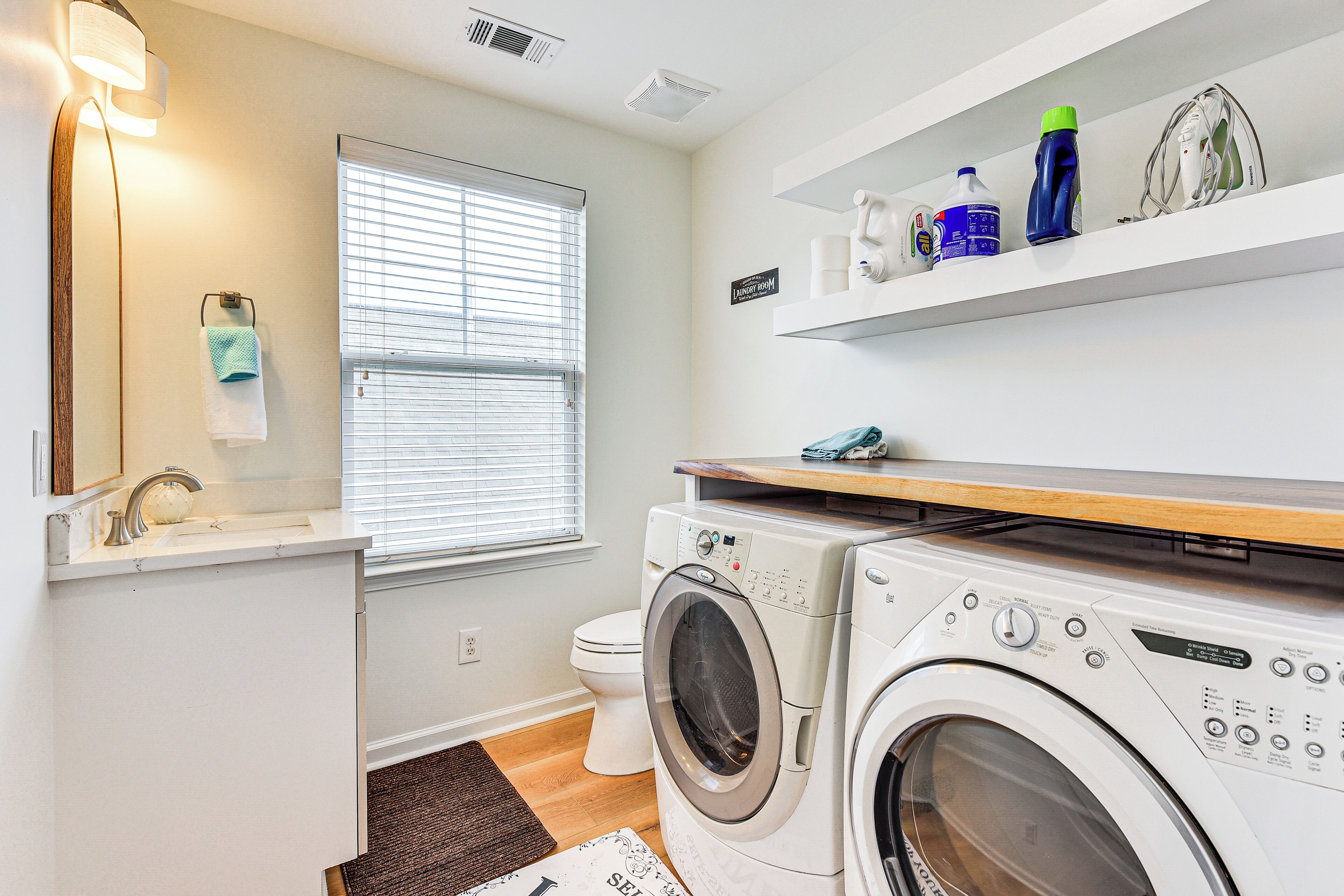 A compact laundry room with a washing machine, dryer, and a shelf with cleaning supplies.