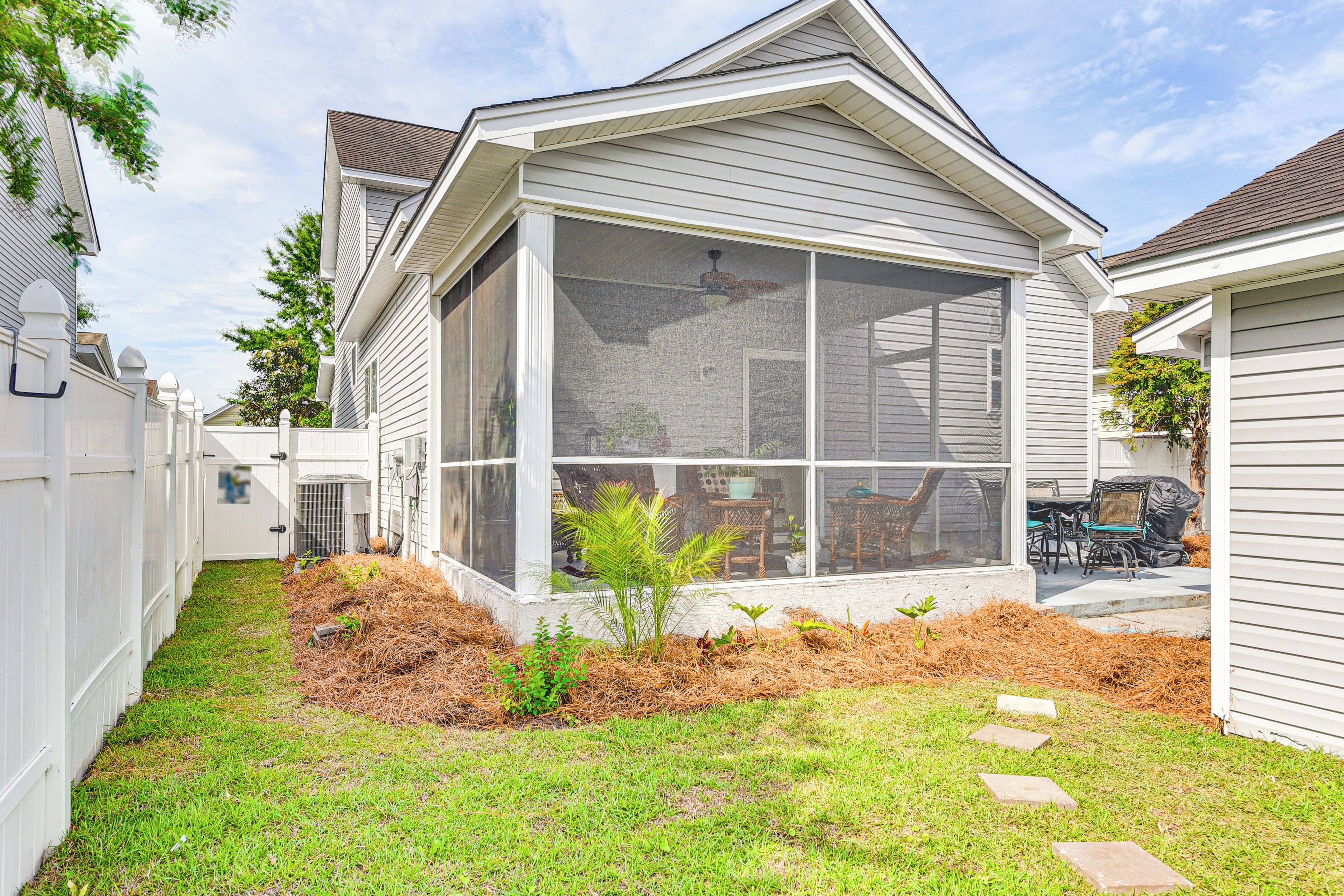 A house with a large screened porch, a fenced yard, and a small garden area.