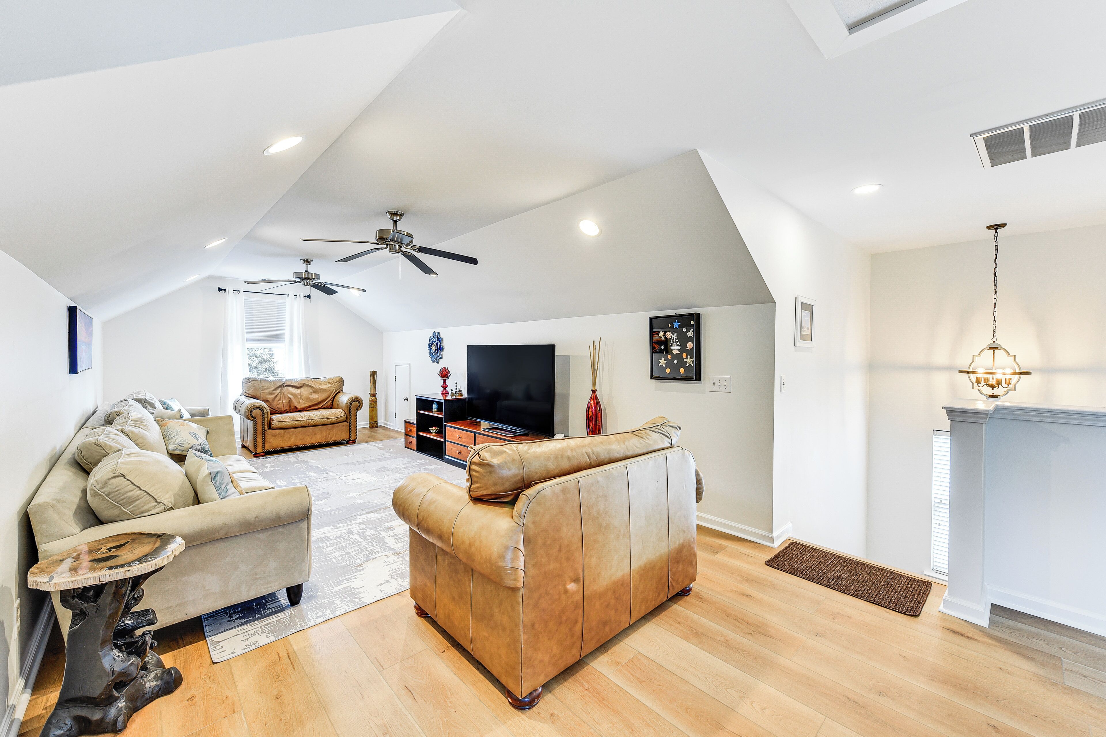 A spacious living room with a high ceiling, a fireplace, and a television.