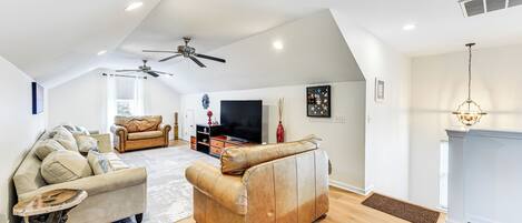 A spacious living room with a high ceiling, a fireplace, and a television.