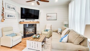 A living room with a fireplace, a ceiling fan, a flat-screen TV, and a sofa. - 3 Mi to Beaches! Charming Bluffton Escape w/ Yard (Bluffton)