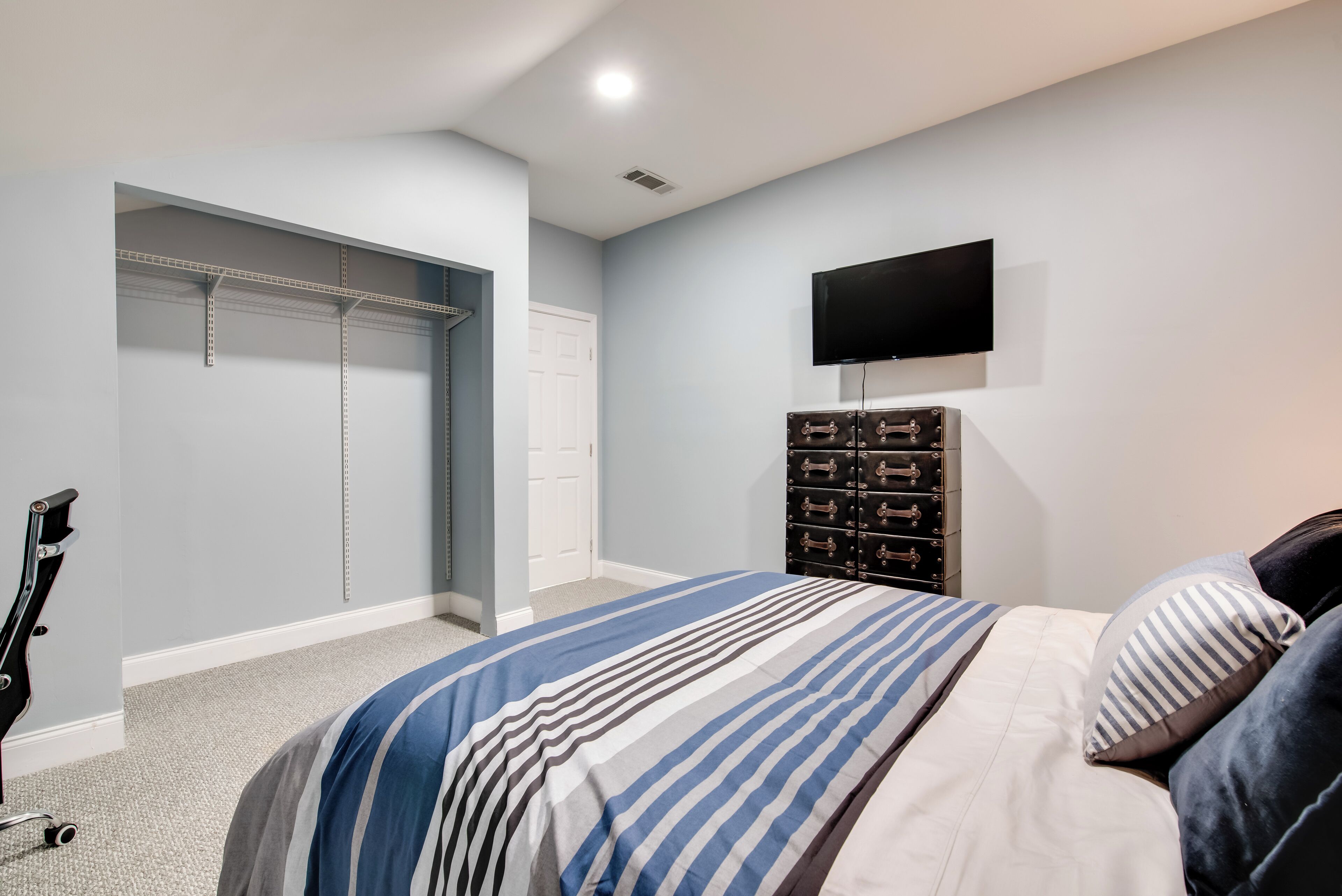A bedroom with a bed, a television, a wardrobe, and a shoe rack.