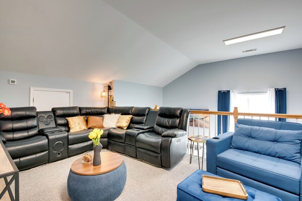 A modern living room with a black leather sectional sofa, a blue armchair, and a round coffee table with a vase of flowers. - Walk to Lake: Hiram Hideaway w/ Shared Gazebo! (Hiram)