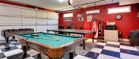 A pool table in a room with a checkered floor, a red wall, and a white ceiling.
