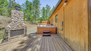 Una cabaña de madera con chimenea de piedra, jacuzzi y terraza.