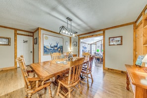 A wooden dining table with chairs, a chandelier, and framed artwork on the walls. - Peaceful Ruidoso Cabin: Hot Tub, Mountain Views! (Ruidoso)