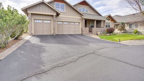 Une maison à deux étages avec un garage, une façade en pierre et une pelouse bien entretenue.