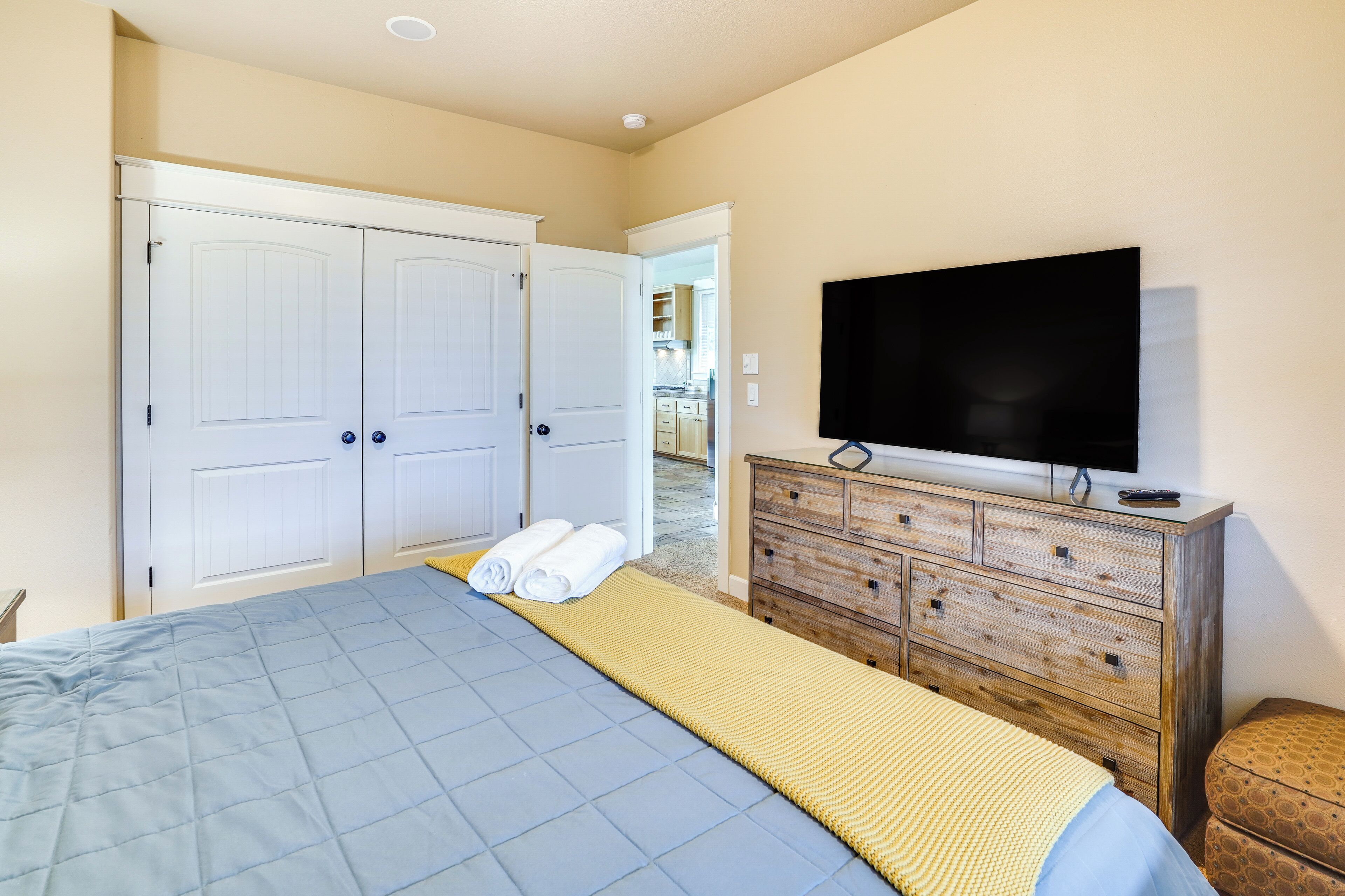 Une chambre à coucher avec un lit, un téléviseur posé sur une commode en bois et une armoire.