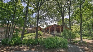 A building with a stone facade and a wooden structure with a roof. There is a paved path leading to the building. - Ski-in/ski-out Wintergreen Resort Condo + Hot Tub! (Nellysford)