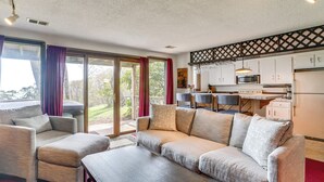A modern living room with a sofa, a coffee table, and a dining area with a table and chairs. - Ski-in/ski-out Wintergreen Resort Condo + Hot Tub! (Nellysford)