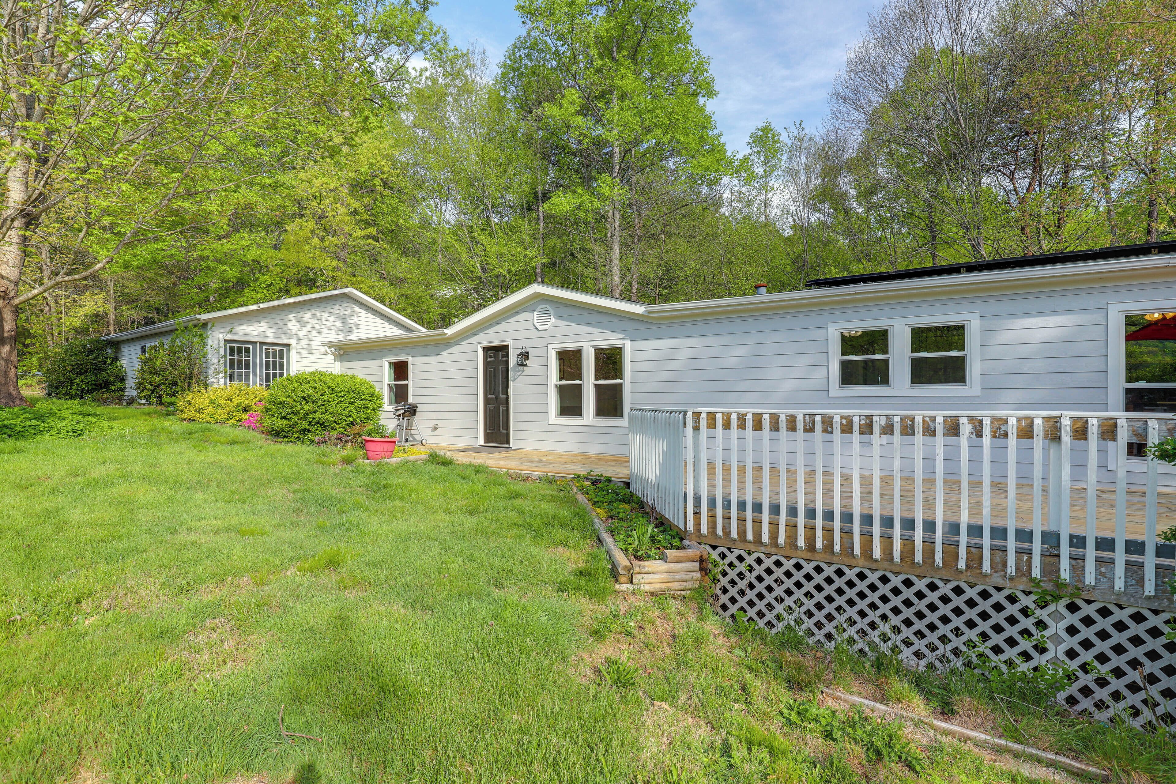 A single-story house with a front porch, a fenced deck, and a well-maintained lawn.