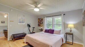 Ein Schlafzimmer mit Bett, Deckenventilator, Fenster, Lampe und einem Gemälde an der Wand.