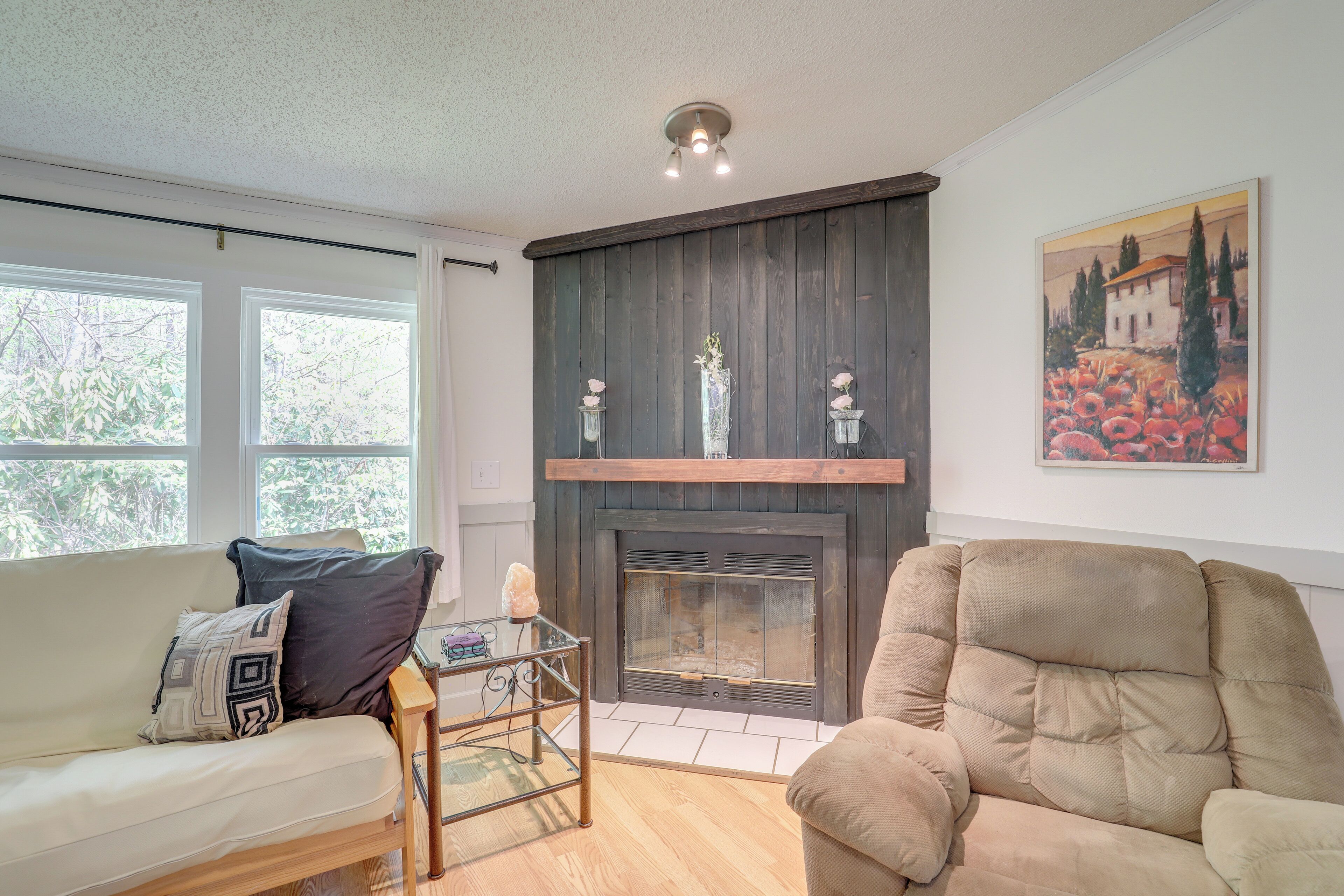 A living room with a fireplace, a sofa, a chair, and a glass coffee table.