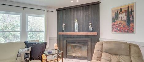 A living room with a fireplace, a sofa, a chair, and a glass coffee table.